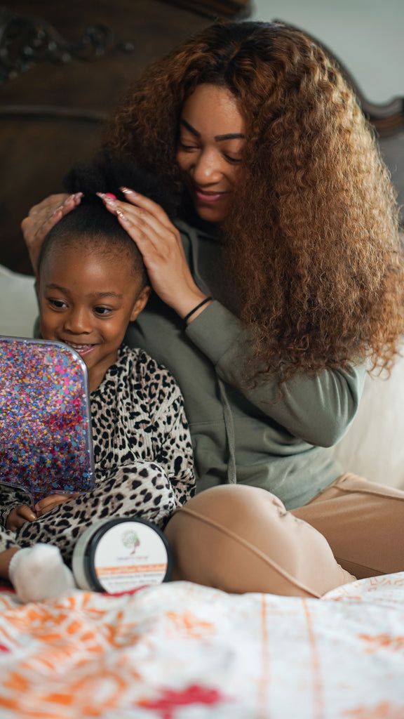 Woman combing conditioner through daughter's hair. 